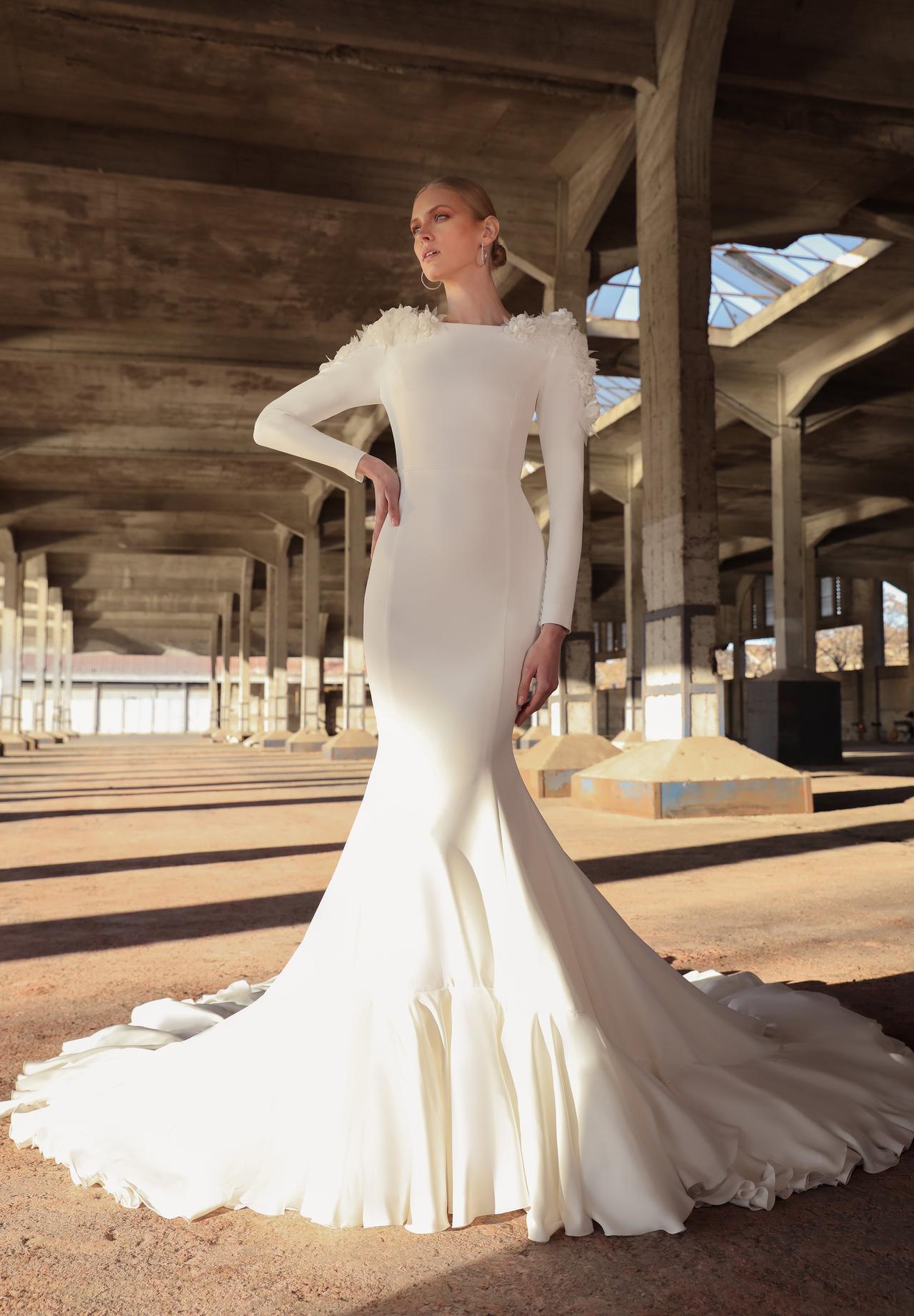 Chica con el pelo recogido con un vestido de novia de aire flamenco con flores en 3D en los hombros