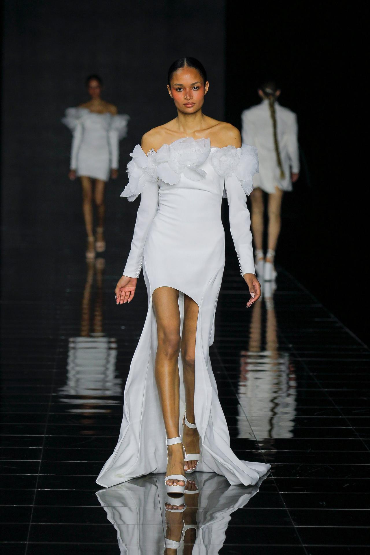 Vestido de novia con cola asimétrica y hombros escotados con volantes