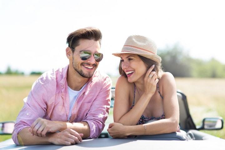 Qué buscas en una pareja: pareja muy sonriente dentro de un coche descapotable