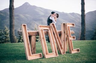 Pareja besándose el día de la boda tras grandes letras en las que puede leerse la palabra Love