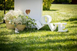Letras lacadas en blanco formando la palabra Love sobre la hierba el día de la boda