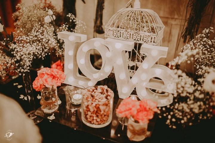 Letras metálicas con iluminación formando la palabra Love en la mesa de dulces el día de la boda
