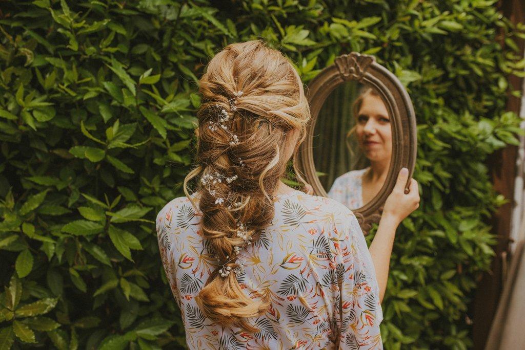 Peinado trenza: chica rubia con un espejo con una bonita trenza desecha con flores