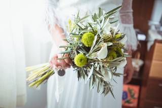 Chica con un vestido de novia sujeta en una de sus manos un precioso ramo de calas de apariencia silvestre