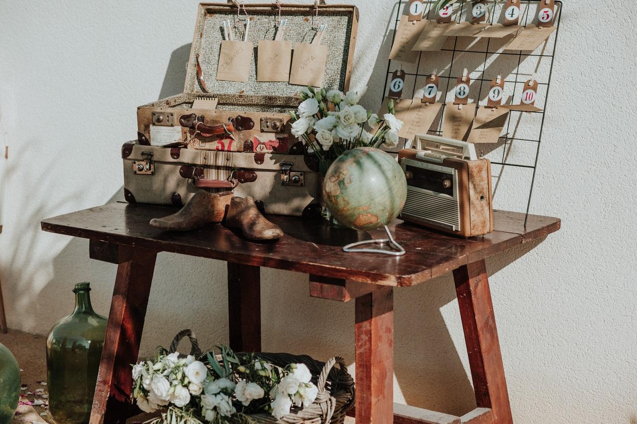 Mesa antigua con decoración de boda vintage: maletas, bola del mundo, radio...