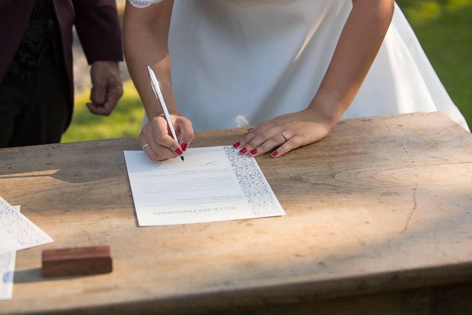 Trámites para casarse: novia firmando el acta matrimonial al final de su ceremonia de boda civil al aire libre