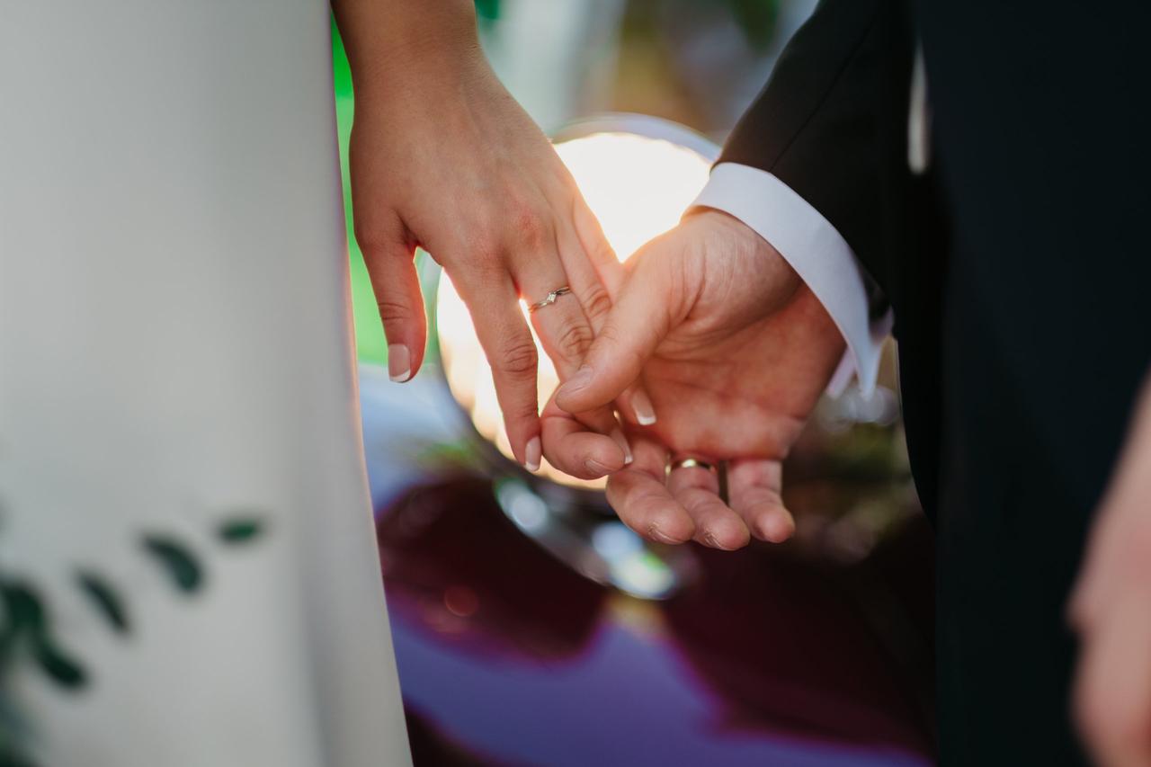 Discurso boda: manos de hombre y mujer con alianzas, entrelazadas