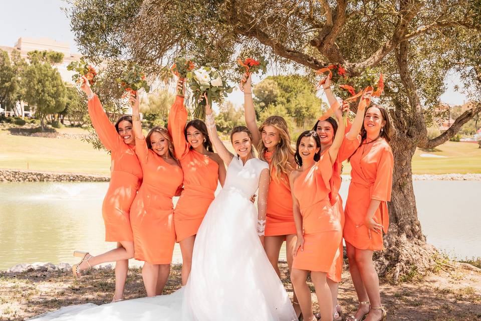 Damas de honor con vestidos naranja con variados diseños con la novia en una divertida fotografía