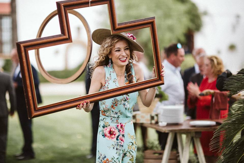 mujer sonriente con un vestido de flores sujetando un marco grande