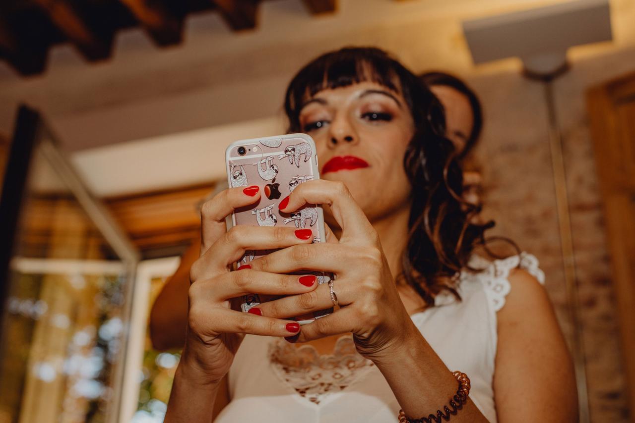 una novia durante sus preparativos preboda enganchada a su teléfono móvil