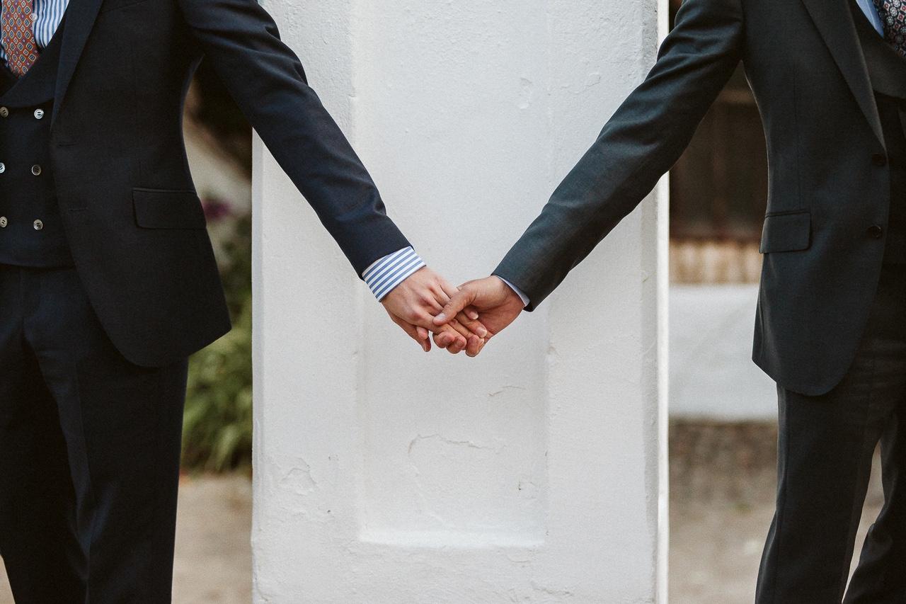 Organizar boda en 3 meses: dos chicos con trajes oscuros se cogen de las manos