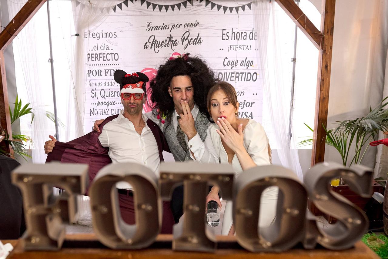 Ideas photocall boda: recién casados e invitado haciéndose una foto divertida