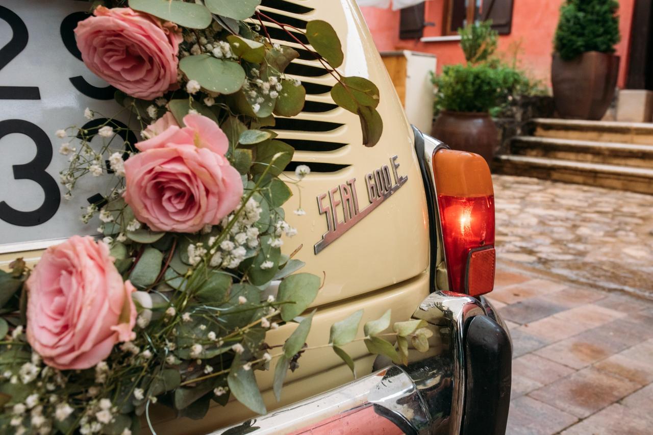 Seat 600 con una corona de rosas de color rosa rodeando la matrícula del vehículo