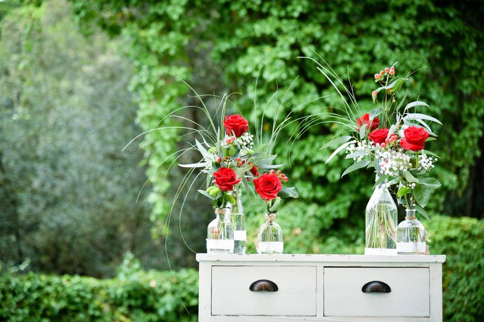 Flores para boda: rincón decorativo con jarrones de distintas formas y tamaños con rosas rojas