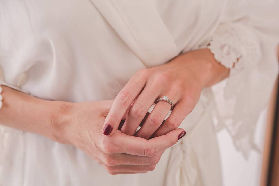 manos de mujer con uñas rojas y anillo de pedida con diamante discreto