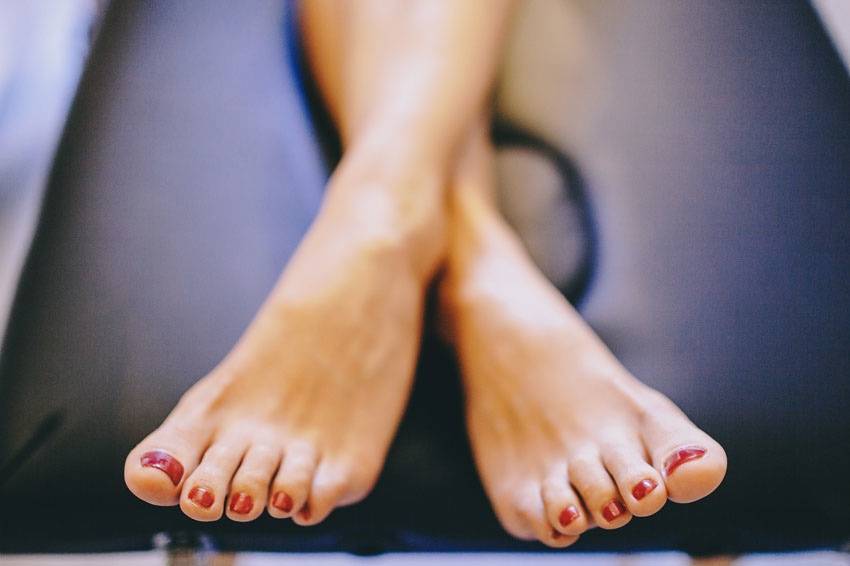 Primer plano de los pies cruzados de una chica con las uñas pintadas de rojp