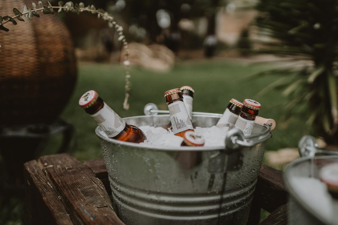 Rincón cerveza boda con cubo de cinc en una estructura de madera con cervezas y cubitos de hielo en su interior