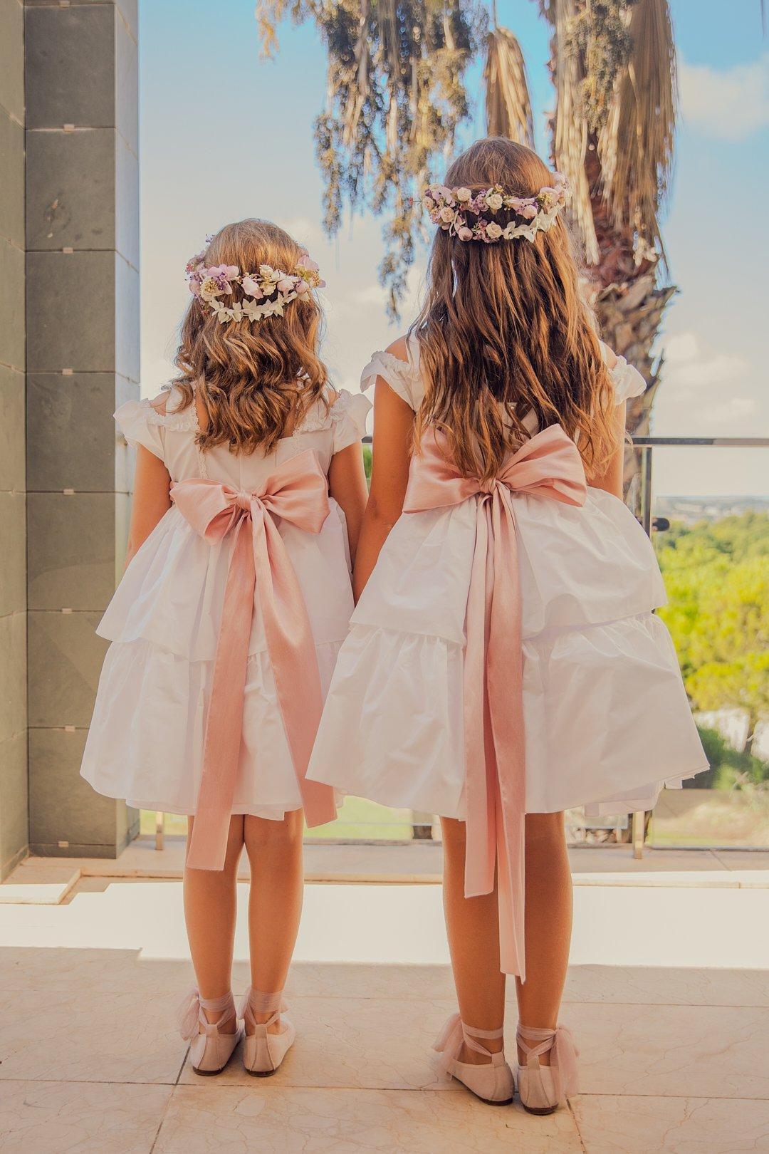 Pajes de una boda o damitas de honor de espaldas luciendo el mismo vestido y tocado de flores en la cabeza