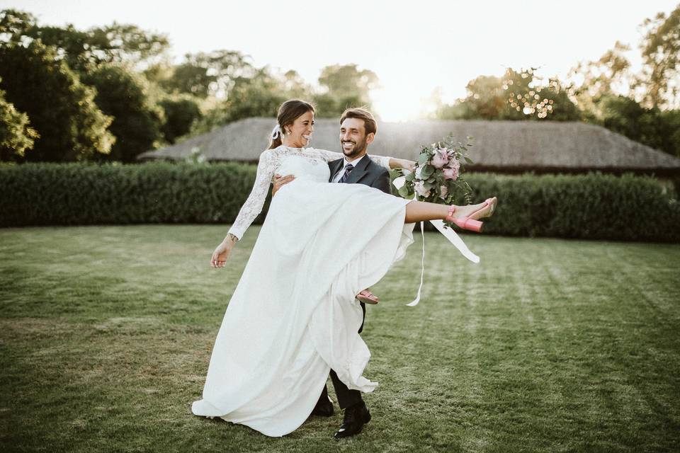 Tipos de boda: chico con traje sujeta a chica vestida de novia en un precioso jardín con césped
