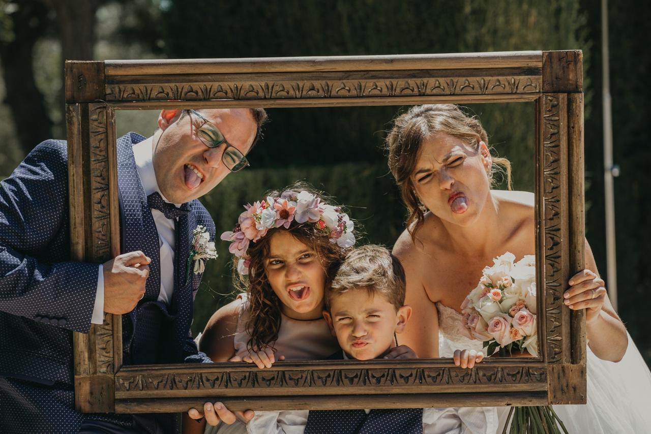 Ideas originales para bodas: dos adultos y dos niños sujetan un marco mientras ponen caras divertidas