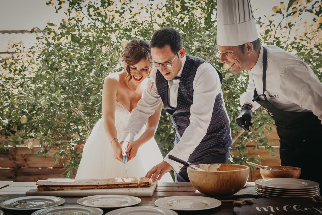 Ideas originales para bodas: pareja de recién casados cortando un postre junto al cocinero
