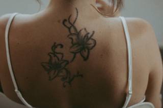 Chica de espaldas con un moño bajo de apariencia sencilla y un tatuaje en la espalda