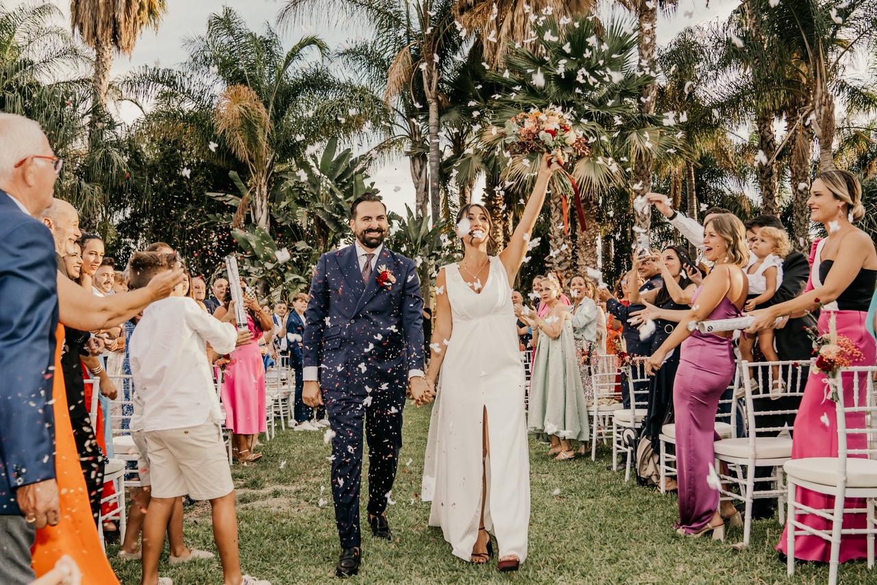 Canciones salida novios: recién casados caminando por el pasillo al acabar su boda civil bajo una lluvia de pétalos de flores