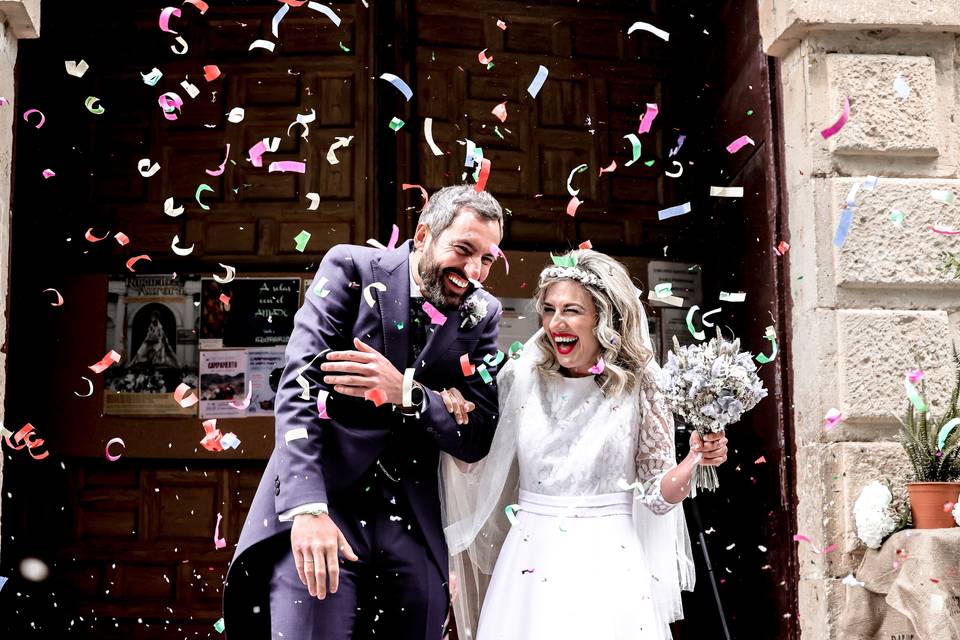 Excusa no ir una boda pareja muy sonriente a la salida de su boda por la iglesia mientras les tiran confeti