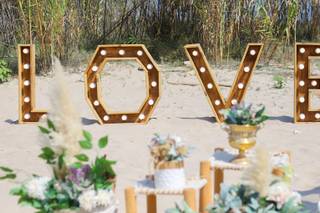 Rincón decorativo de una boda en la playa con grandes letras luminosas formando la palabra Love