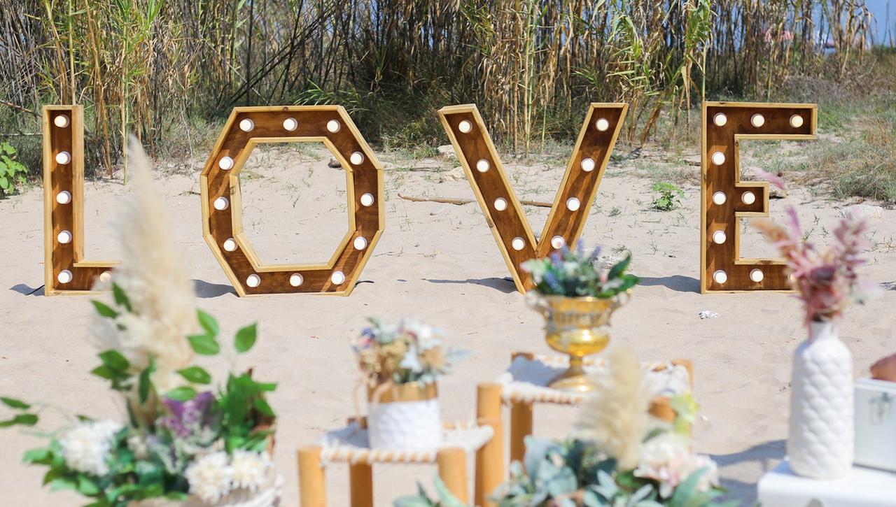 Rincón decorativo de una boda en la playa con grandes letras luminosas formando la palabra Love