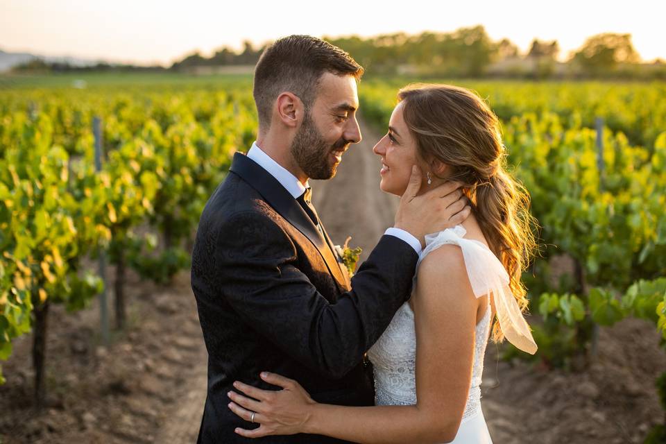 Pareja de recién casados se mira sonriente y se abraza en medio de un viñedo