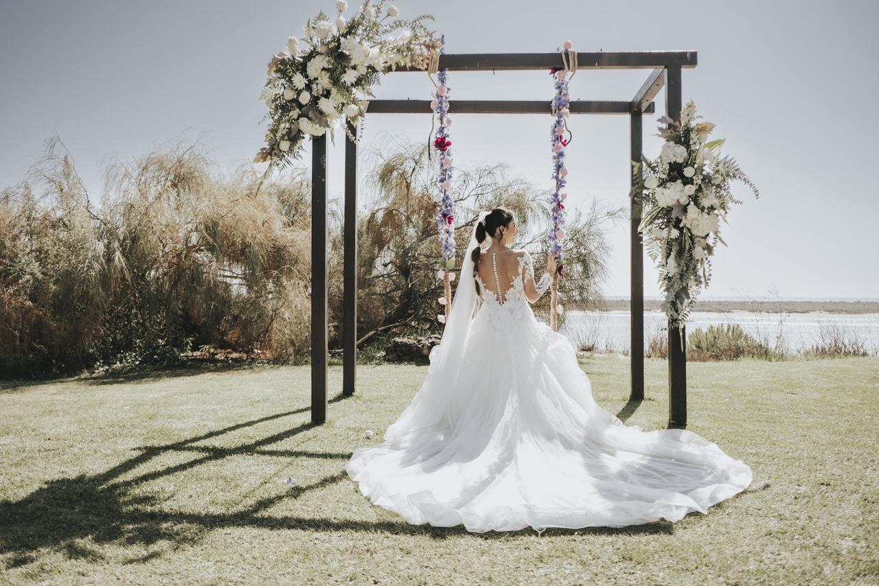 Decoración boda exterior: novia de espaldas en un columpio lleno de flores