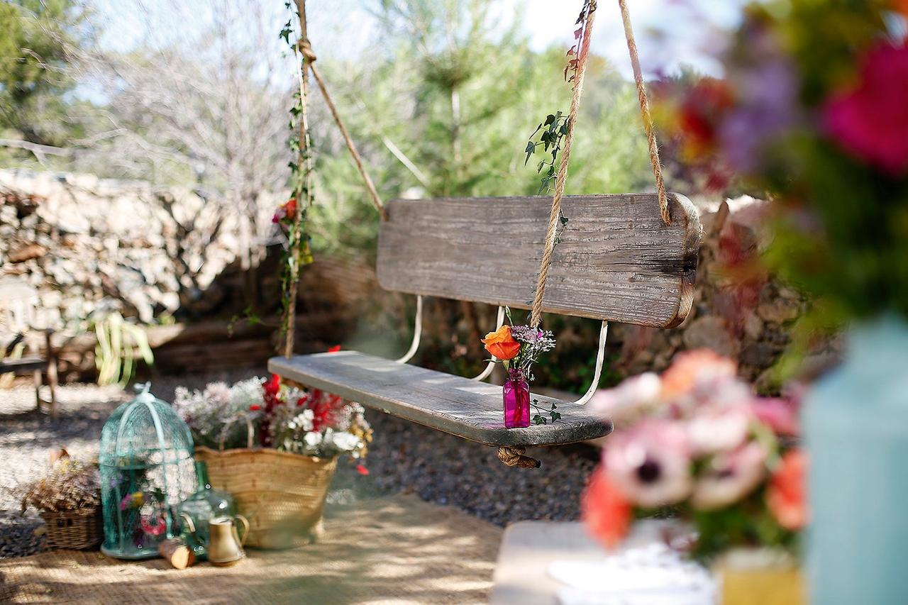 Decoración boda exterior: precioso rincón decorativo al aire libre con un columpio de madera adornado con muchas flores