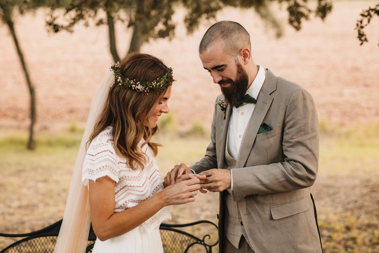 Pareja de novios durante el intercambio de alianzas en la boda