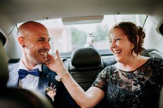 Madrinas de boda: novio y madrina felices y sonrientes en el interior de un coche, camino a su boda