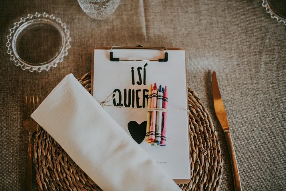 Mesa preparada para los niños de una boda con cuadernos para colorear y pinturas encima de cada mantel individual