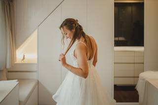 Chica con un vestido blanco en una habitación se sujeta un mechón del pelo