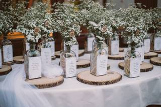 Seating plan original con botellas de cristal con ramilletes en su interior y el nombre de los invitados asignados en cada mesa