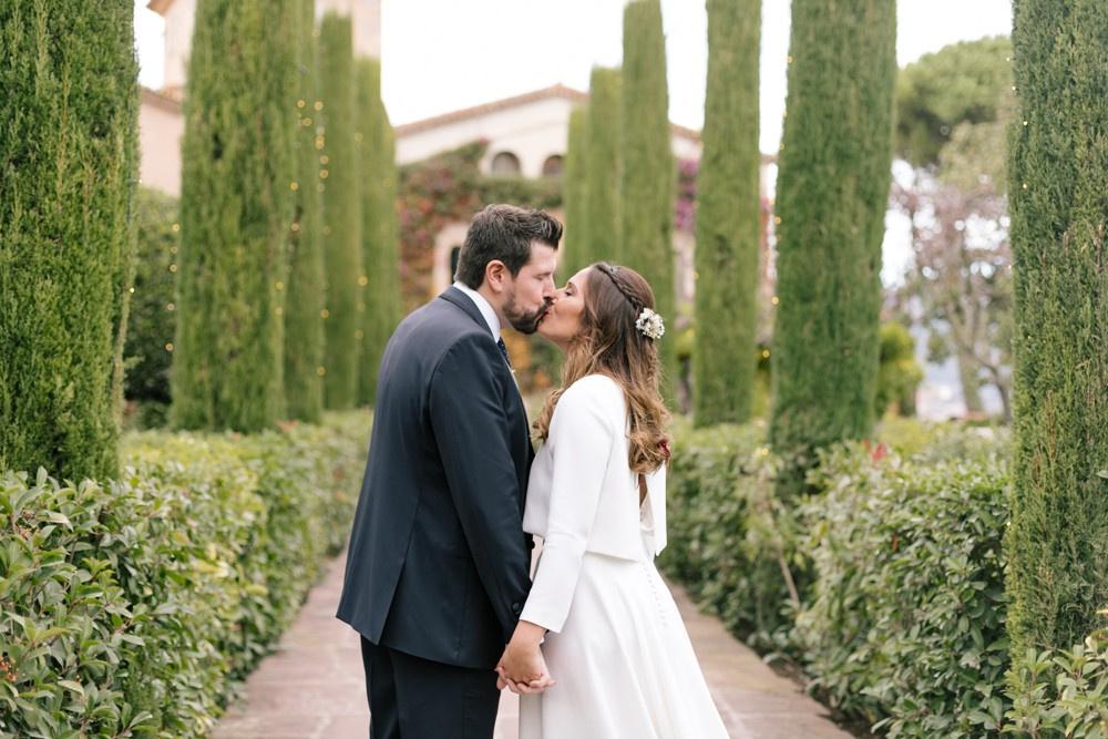 Boda low cost: pareja de recién casados se besa en un camino rodeados de árboles y vegetación