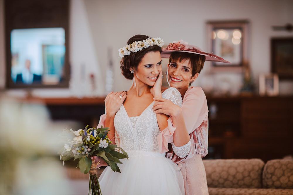 Madre muy elegante e hija vestida de novia se abrazan muy sonrientes