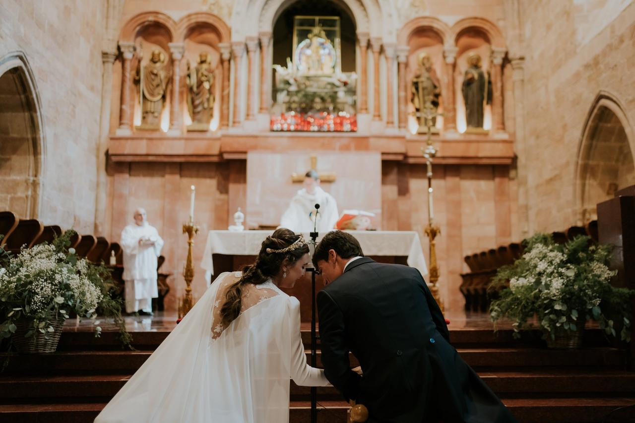 Novio y novia comentan algo en el altar el día durante la ceremonia religiosa