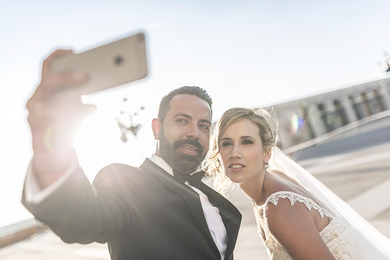 selfie de pareja con un móvil engalanados con el vestido de novia y el traje de novio