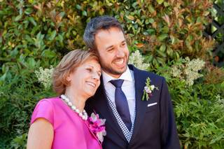 Madrinas de boda: novio y madrina posan felices delante de vegetación