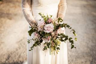 Chica con vestido de novia sujetando un original y desestructurado ramo de novia con varias rosas de color rosa