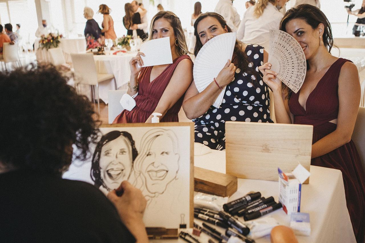 caricaturista retratando a tres chicas que se tapan la cara con un abanico