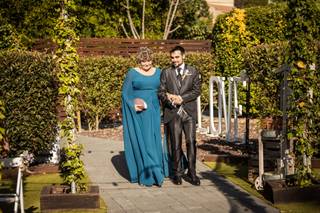 Madrinas de boda: novio y madrina cogidos del brazo y caminando por un exterior al aire libre