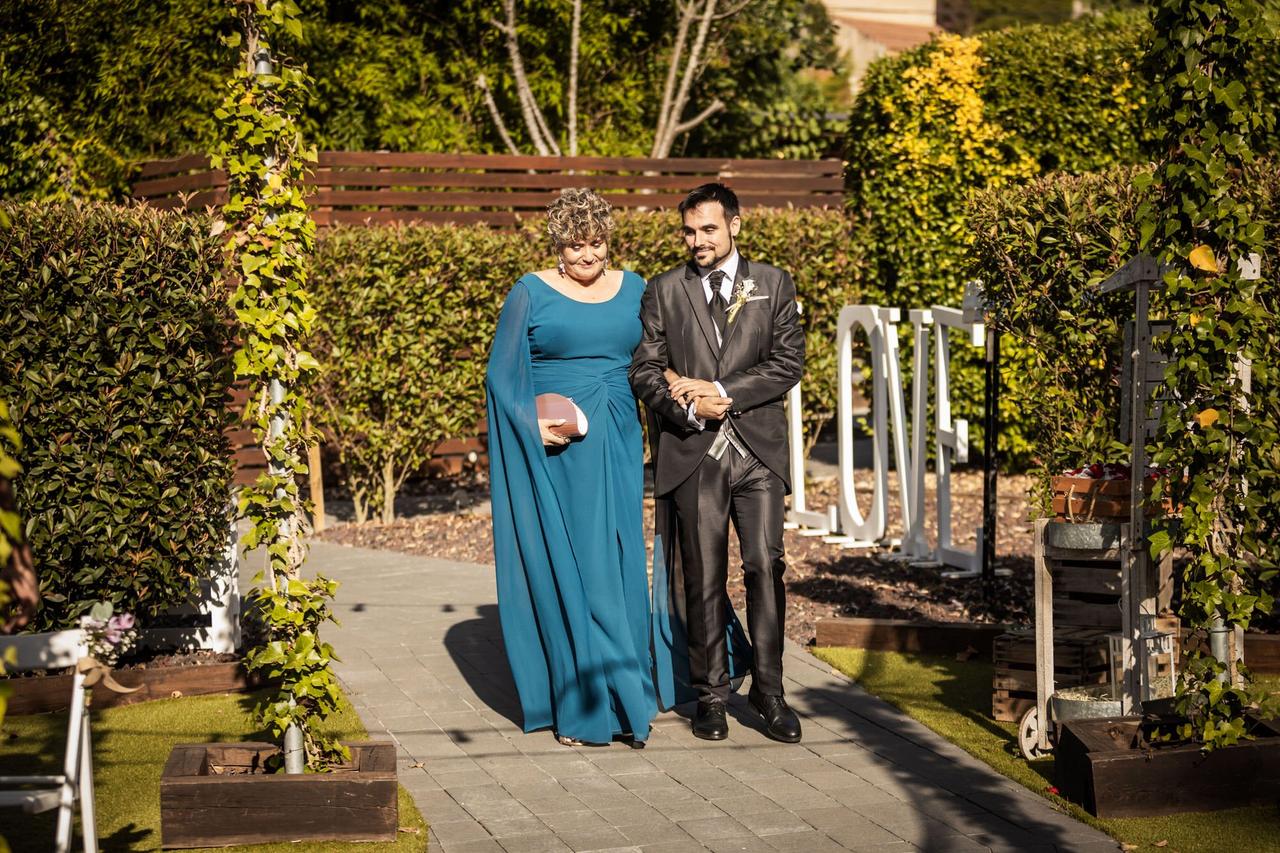 Madrinas de boda: novio y madrina cogidos del brazo y caminando por un exterior al aire libre