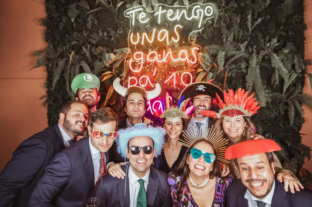 Ideas photocall boda: invitados haciéndose una foto en el rincón de photocall, bajo un neón