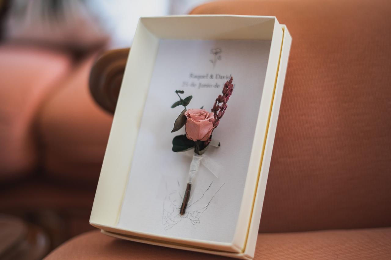 Bonita presentación de un prendido de novio con rosa en una caja