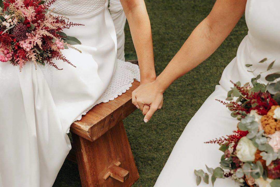 Dos novias se cogen la mano en el altar de su ceremonia civil al aire libre